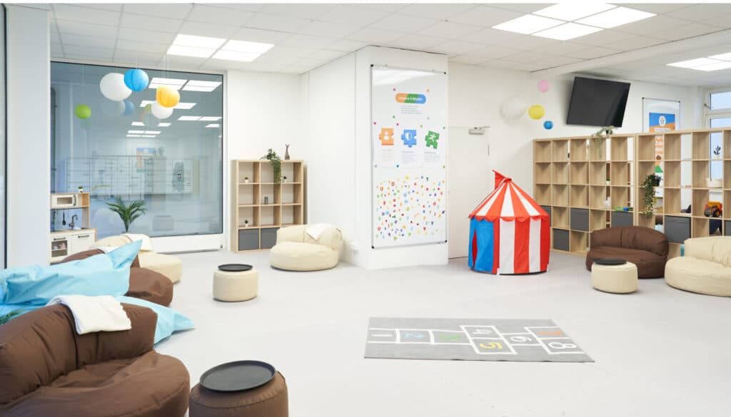 Aufenthaltsbereich mit Sofas, Spielteppich und Kinderzelt