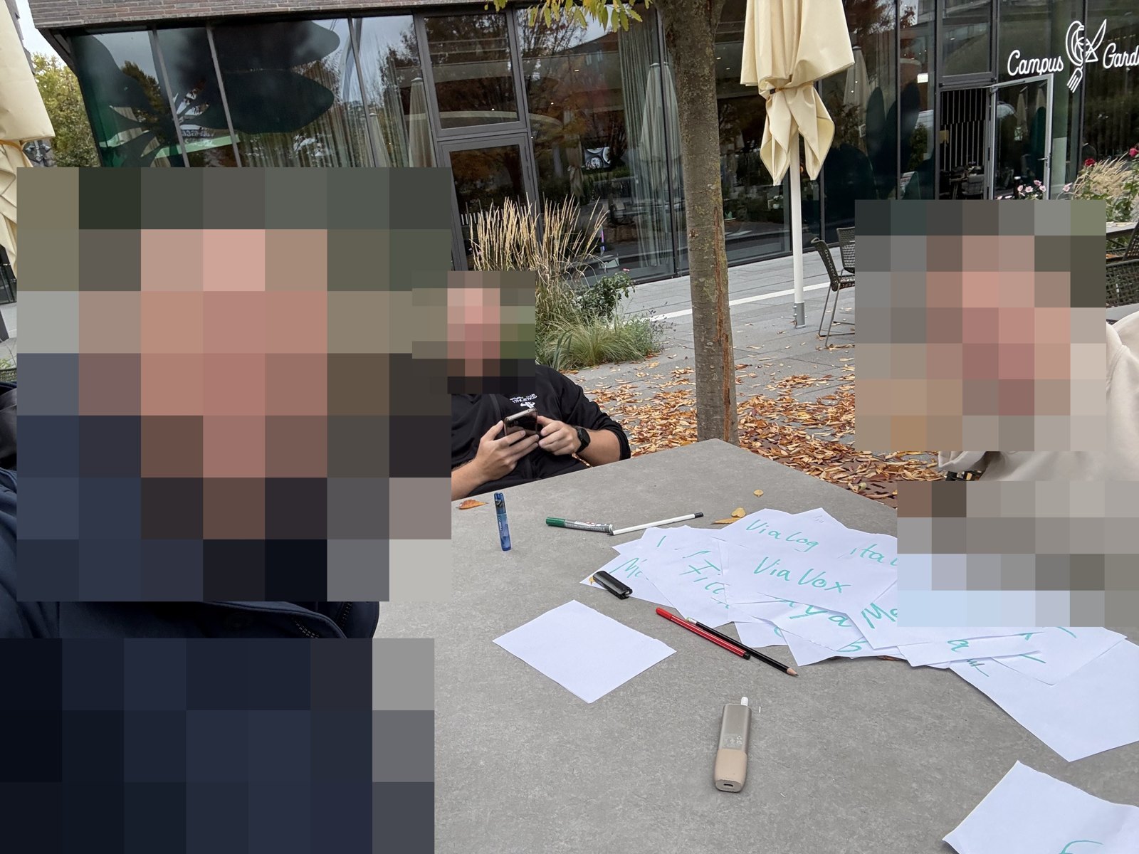 Die Runde am Tisch beim Kartenlegen; die Gesichter sind unkenntlich gemacht